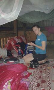 Kobieta siedząca na legowisku pod moskitierą na strychu.