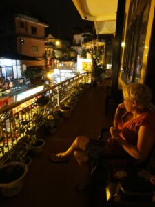 Kobieta siedząca nocą na balkonie z widokiem na oświetloną Sapę.