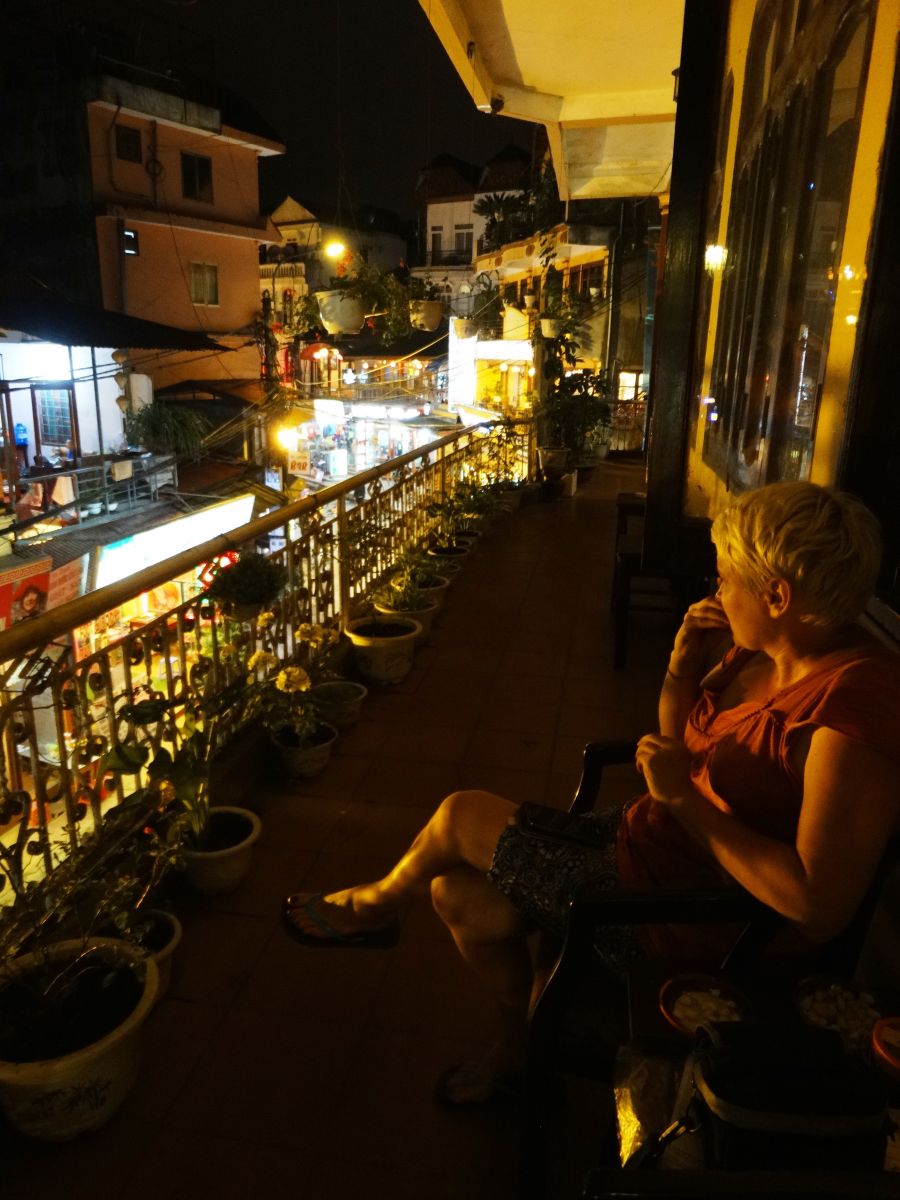 Kobieta siedząca nocą na balkonie z widokiem na oświetloną Sapę.